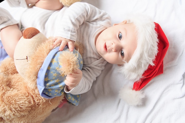 Nettes Baby im Weihnachtsmannkostüm mit einem Spielzeug