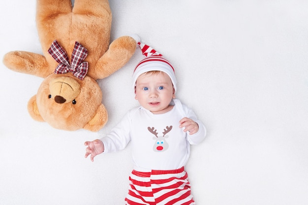 Nettes Baby im Weihnachtsmannkostüm und im großen Teddybär