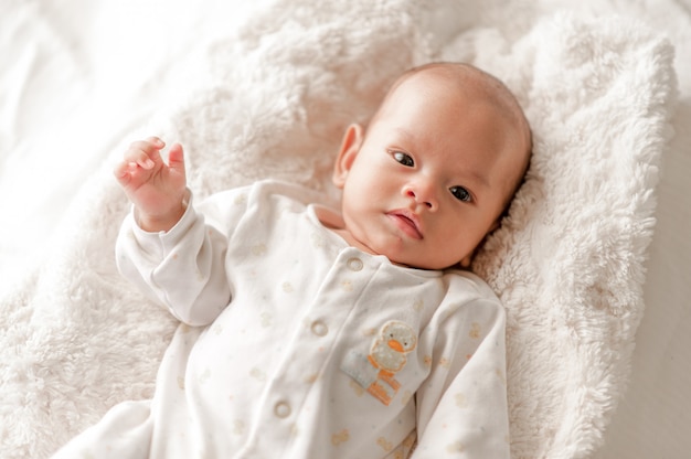 Nettes Baby in einem Schlafzimmer des weißen Lichtes Neugeborenes Baby ist nett. In Bettwäsche für Kinder geboren - Bilder