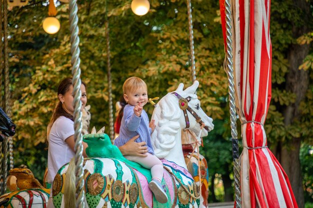 Nettes Baby mit Mutter auf dem Pferd des alten Retro-Karussells Prag Tschechien