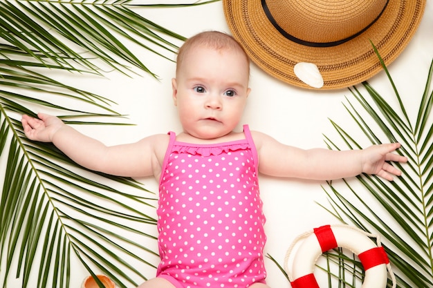 Nettes Baby mit Strandzubehör auf hellem Hintergrund. Urlaub auf See mit Baby, Sommerkonzept