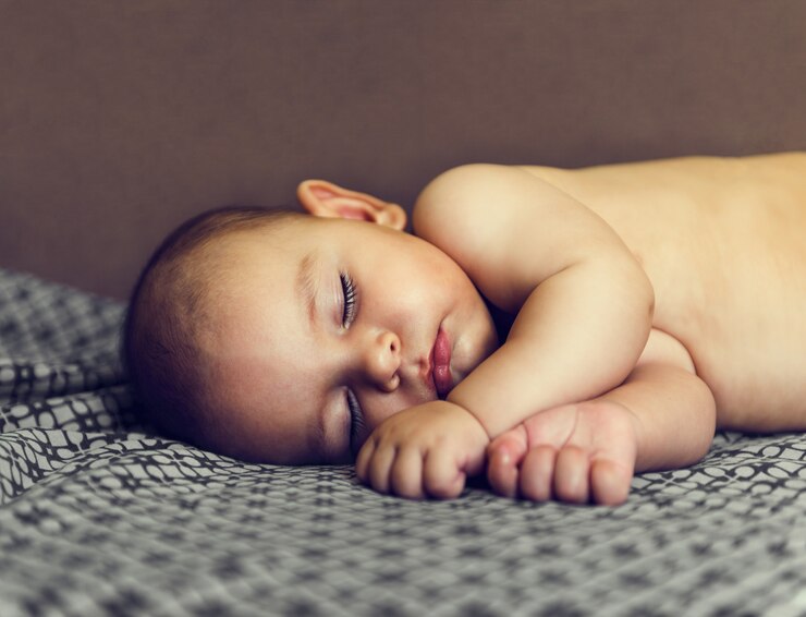 Nettes Baby schläft auf nacktem Bettbraun des seitlichen Sommers