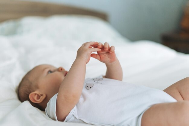 Nettes Babymädchen 24 Monate auf Bett mit selektivem Fokus der weißen Leinennaturtöne