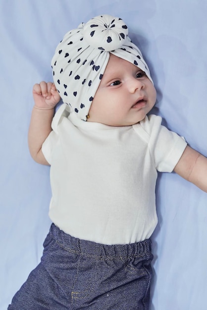 Nettes Babymädchen, das modisches Baby in einem Turban aufwirft