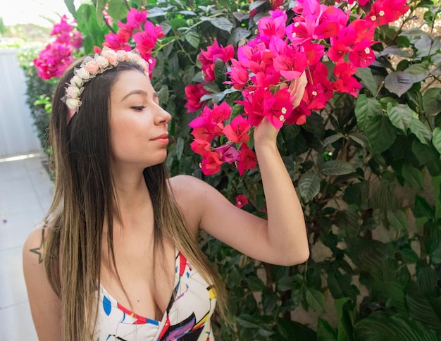 Nettes brünettes Teenager-Mädchen mit geblümter Tiara oder Haarband im Garten. Hippie-Kostümkonzept.