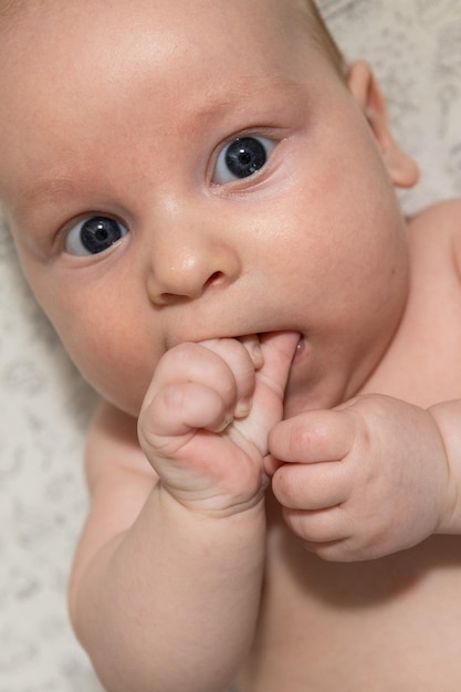 nettes drei Monate altes Baby, das seine Hand isst Zahnen