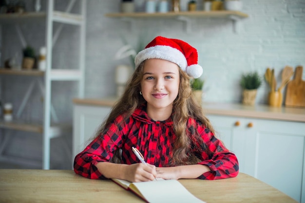 Foto nettes entzückendes lächelndes mädchen in der weihnachtsmannmütze zu hause