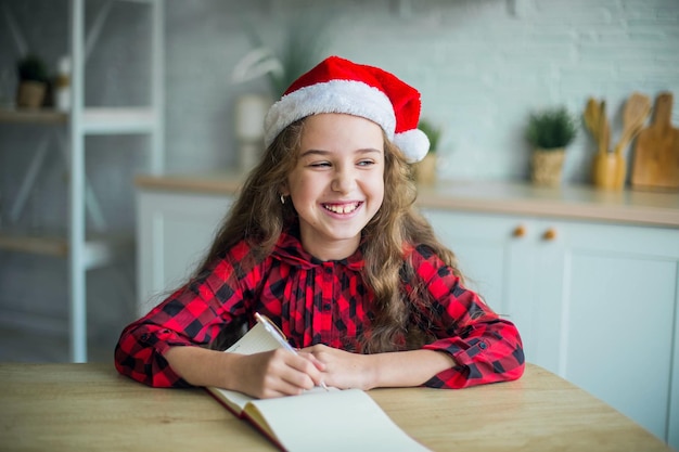 Foto nettes entzückendes lächelndes mädchen in der weihnachtsmannmütze zu hause