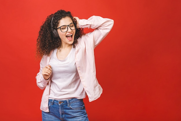 Nettes fröhliches lockiges brünettes Studentenmädchen, das Musik hört, tanzt