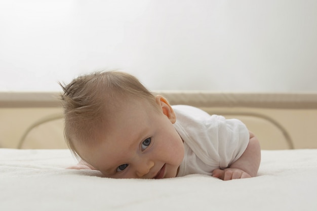 Nettes glückliches Baby, das im Bett sitzt