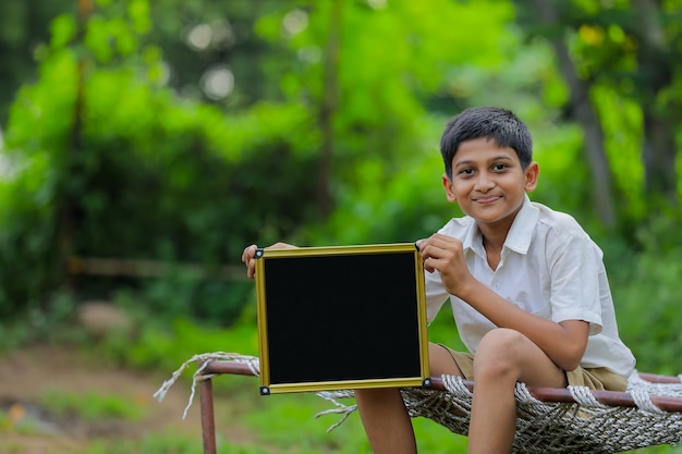 Nettes indisches kleines Kind, das Tafel mit Kopienraum zeigt