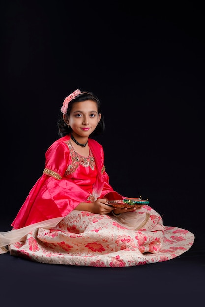 Nettes indisches kleines Mädchen, das Diya- oder Öllampen für Diwali-Feier hält.