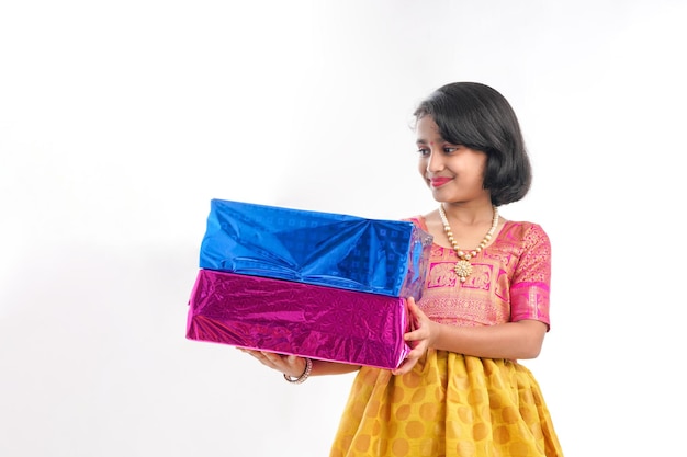 Nettes indisches kleines Mädchen Kind mit Geschenkboxen in traditionellen Tüchern, die isoliert über weißem Hintergrund stehen
