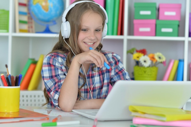 Nettes jugendlich Mädchen, das am Tisch sitzt und Laptop benutzt