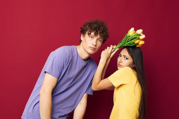 Nettes junges Paar Geschenk Blumenstrauß Spaß roten Hintergrund unverändert