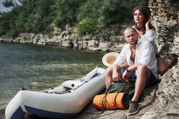 Nettes junges und Paar auf Fluss. Ein Mann und eine Frau mit Rucksäcken reisen mit dem Boot. Traveller Sommerkonzept