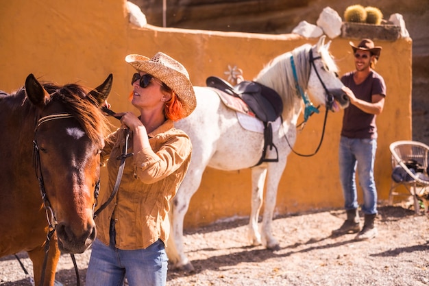 Nettes kaukasisches Paar im Freien bereitet und überprüft Pferdeausrüstungen, die bereit sind, eine neue Abenteuerreise auf alternative Weise zu leben, um natürliche Wege und Konzepte des Weltlandlebens für junge Menschen zu entdecken