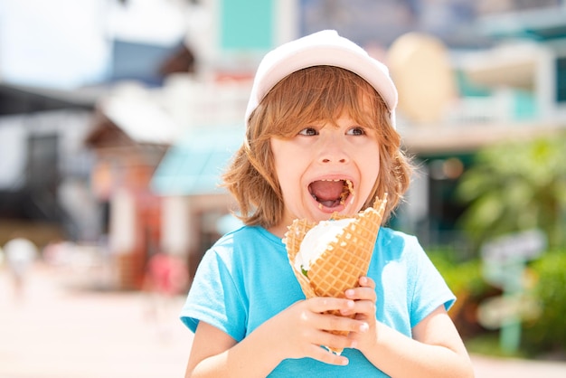 Nettes Kind, das großes Eis im Waffelkegel leckt, das glücklich auf Outdoor-Hintergrund lacht.