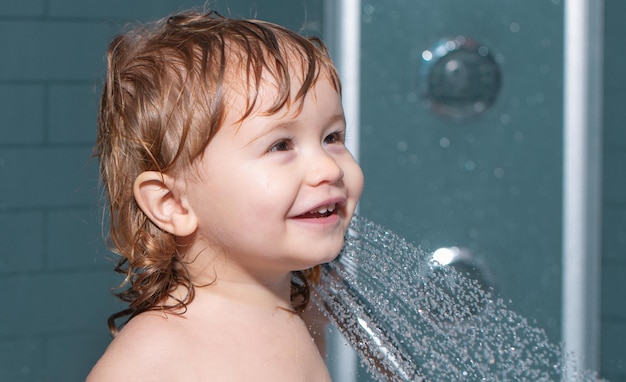 Nettes Kind, das in der Badewanne spielt, Babyduschenporträt des Kindes, das in einer Badewanne mit Schaum badet