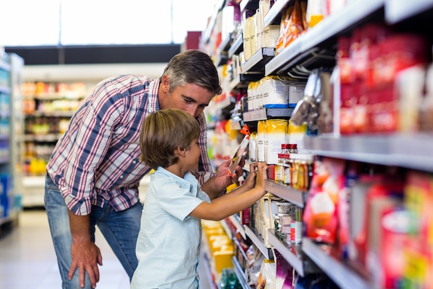 Nettes Kind, das Lebensmittel vom Regal auf Supermarkt wählt