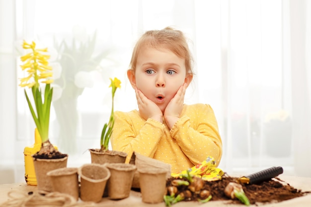 Nettes Kind sieht gelbe Blume überrascht aus. Spielen, studieren und zu Hause im Garten arbeiten, Kindergarten, Vorschulklasse