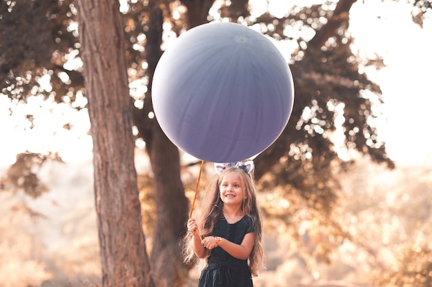 Nettes Kindermädchen, das draußen großen Ballon hält