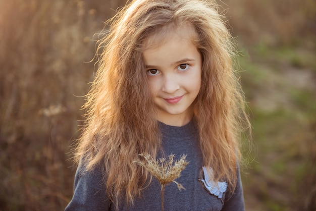 Nettes Kindermädchen, das eine trockene Blume hält. Herbstzeit