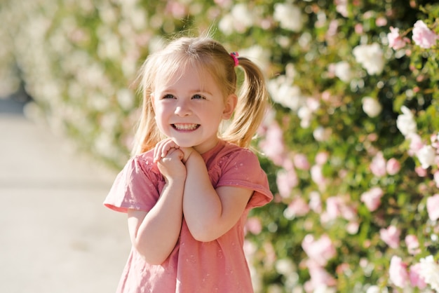 Nettes Kindermädchen mit dem blonden Haar, das über der Natur posiert