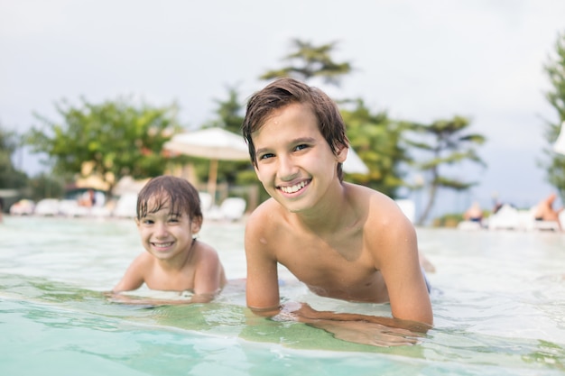 Nettes Kindkind des kleinen Jungen, das im Swimmingpool hat Spaßfreizeitaktivität spritzt