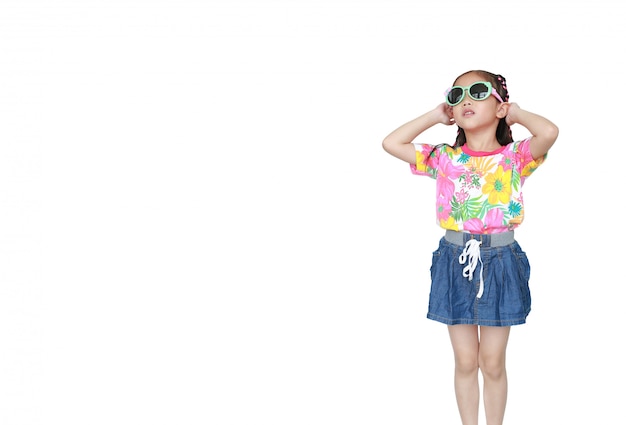 Nettes kleines asiatisches Kindermädchen, das ein Blumensommerkleid und eine Sonnenbrille lokalisiert trägt. Bereit für die Sommerferien.