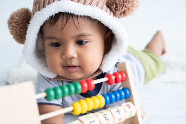 Foto nettes kleines asin baby, das mit hölzernem spielzeug spielt