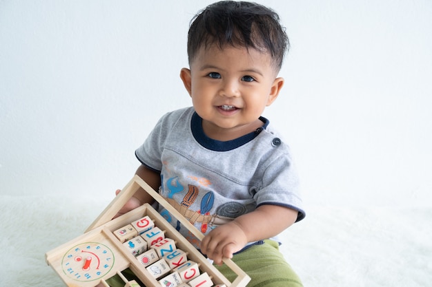 Foto nettes kleines asin baby, das mit hölzernem spielzeug spielt