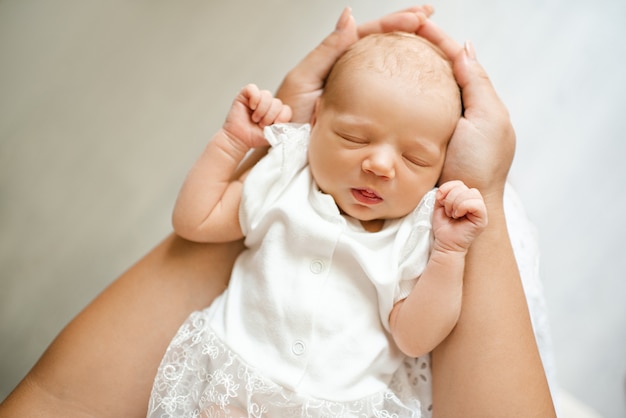 Nettes kleines Baby, das auf Mutterhänden schläft