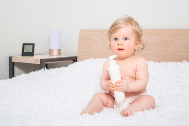 Nettes kleines Baby mit Flasche Babyöl im Elternschlafzimmer.