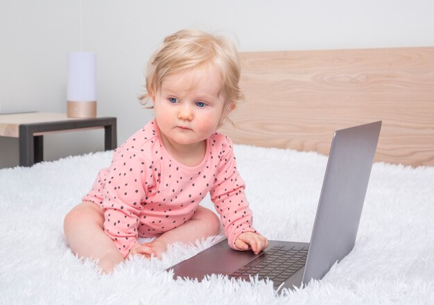 Nettes kleines baby mit laptop im elternschlafzimmer