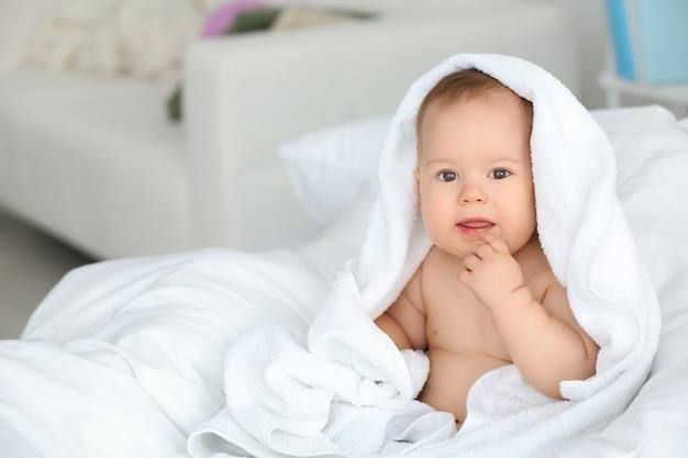 Nettes kleines Baby mit weichem Handtuch zu Hause