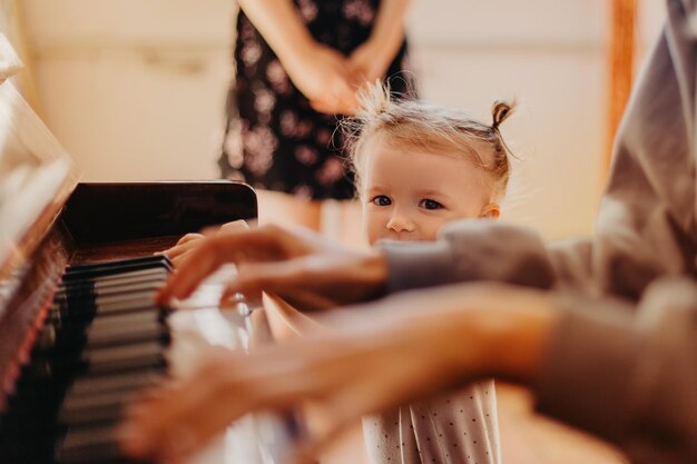 Nettes kleines glückliches Mädchen, das Klavier in einem hellen Raum spielt Selektiver Fokusrauscheffekt