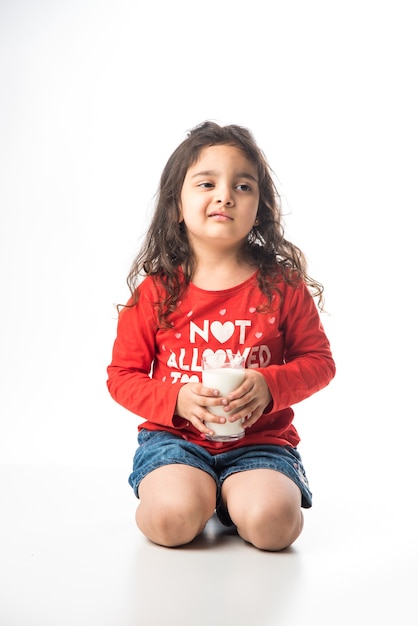 Nettes kleines indisches asiatisches Mädchen, das ein Glas voll Milch hält - Konzept der gesunden Ernährung