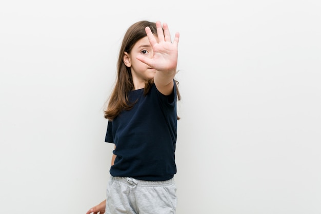 Nettes kleines kaukasisches Mädchen, das mit ausgestreckter Hand steht und Stoppschild zeigt, das Sie verhindert.