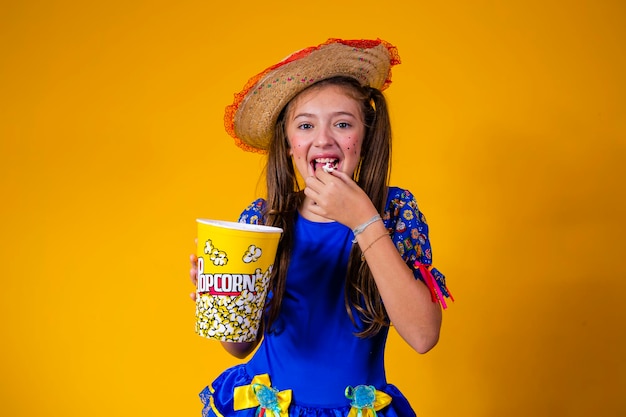 Nettes kleines kaukasisches Mädchen im typischen Festa-Junina-Outfit, das Popcorn isst