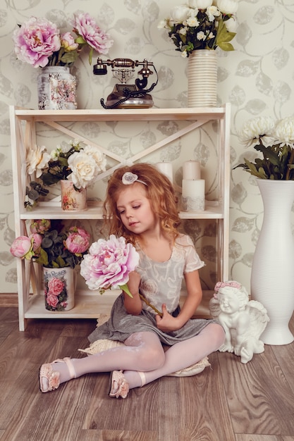 Nettes kleines Kindermädchen mit Frühlingsblumen, glückliches Baby mit Blumenkorb.