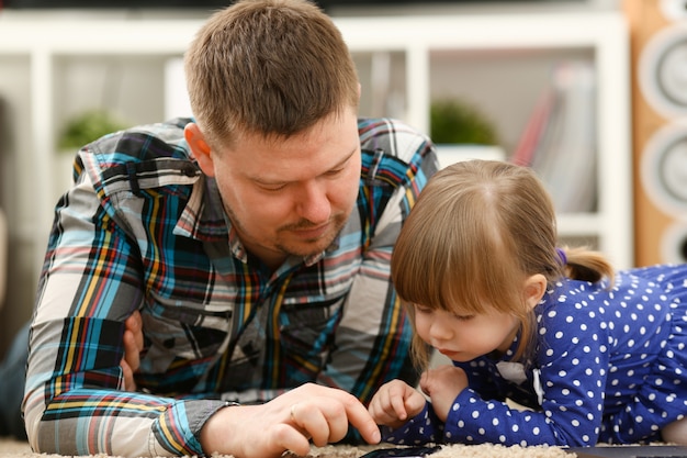 Nettes kleines Mädchen auf Bodenteppich mit Papa