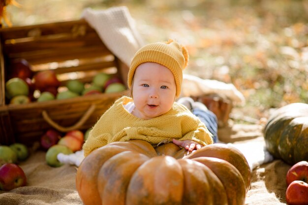 Nettes kleines Mädchen, das auf Kürbis sitzt und im Herbstwald spielt