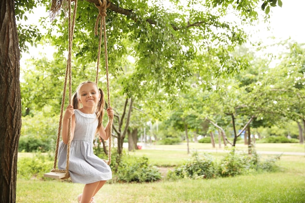 Nettes kleines Mädchen, das auf Schaukeln im Park spielt