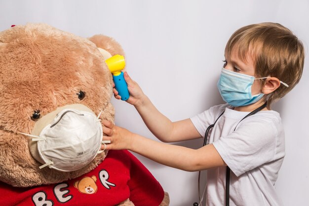 Nettes kleines Mädchen, das Doktor mit Teddybär spielt