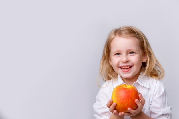 Nettes kleines Mädchen, das einen Apfel auf einem weißen Hintergrund hält