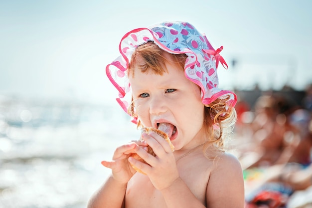 Nettes kleines Mädchen, das Eis am Strandurlaub isst