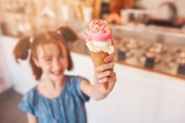 Nettes kleines Mädchen, das Eiscreme in der Cafeteria isst Kind, das Eis hält Kind und Süßigkeiten