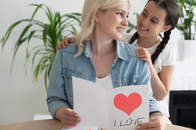 Nettes kleines Mädchen, das ihre Mutter zu Hause grüßt. Muttertagskonzept.