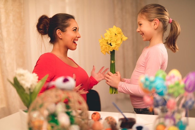 Nettes kleines Mädchen, das ihrem Mutterblumenstrauß gelbe Narzissen gibt.